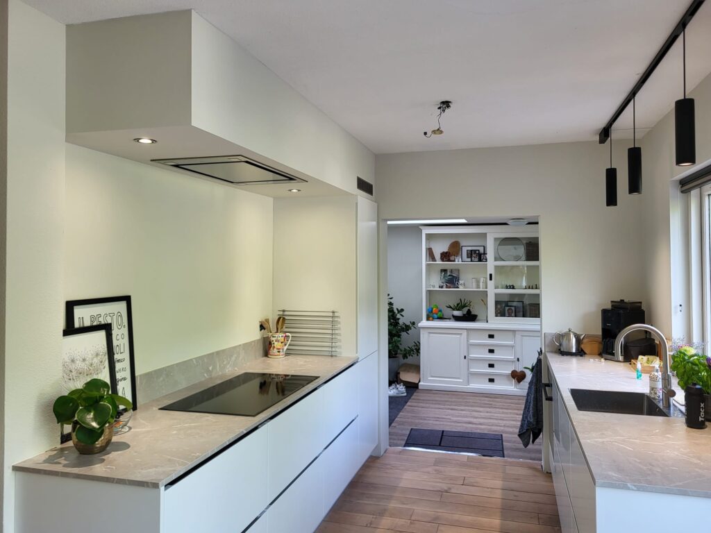 Moderne keuken met wit kookeiland, houten vloer en strak afgewerkte wanden en plafond