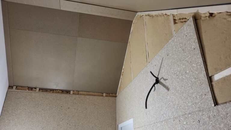 Houtvezelplaat aangebracht tegen de schuine dakkant, naast een afgewerkte wand