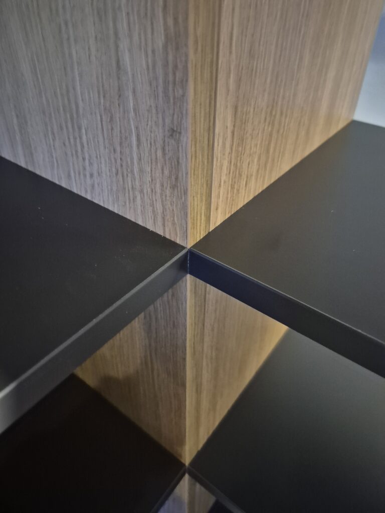 Detailopname van de boekenkast, met een lichte houten staander en donkere legplanken
