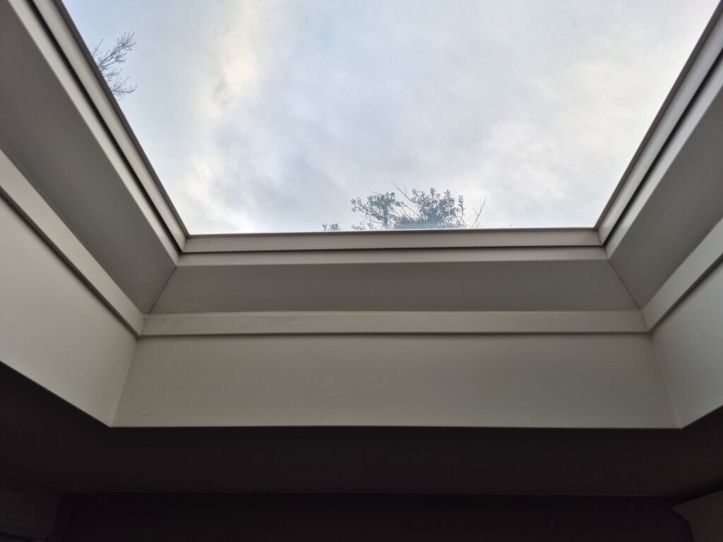 Dakraam met een strak afgewerkte witte plint rondom en uitzicht op de lucht