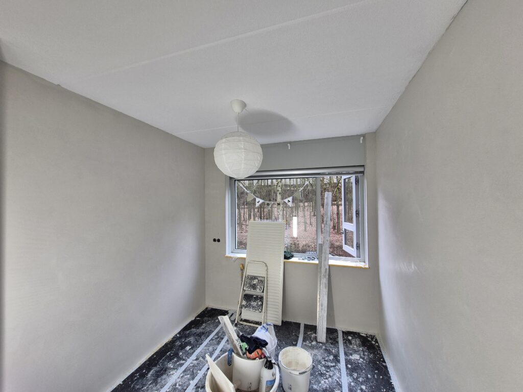 Kleine slaapkamer met vers gestucte wanden rondom het raam